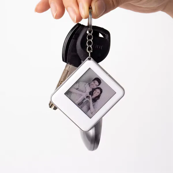 Person's hand holding the Pixelcasee E Ink keychain featuring a custom design, E ink tag